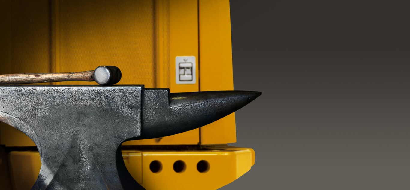 A hammer and anvil sit against a piece of construction equipment