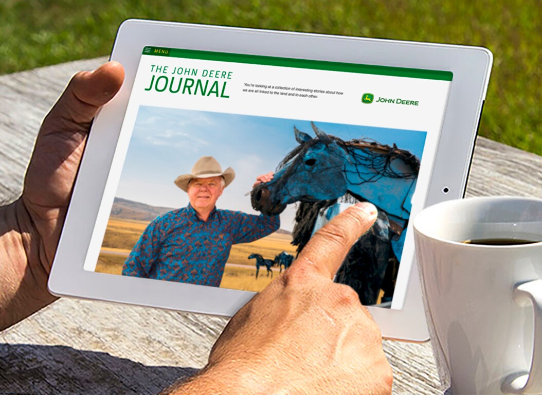 A pair of hands hold and iPad that displays an article from the John Deere Journal