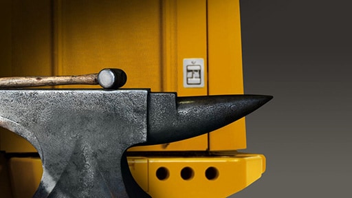 A hammer and anvil sit against a piece of construction equipment