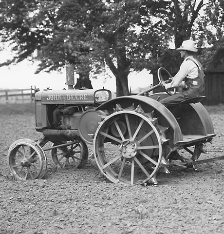 Ein historischer John Deere „GP“-Allzwecktracktor zieht eine John Deere Bodenfräse Nr. 7 im Feld