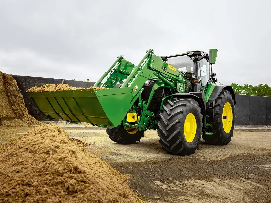 Godet d’un chargeur frontal rempli d’ensilage sur un tracteur John Deere lors d’opérations de manutention.