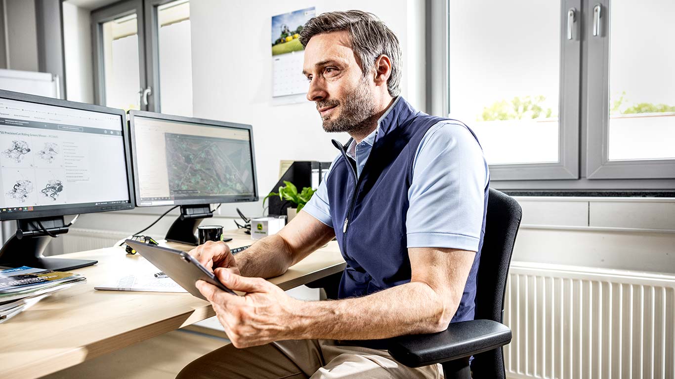 Ein Head Greenkeeper nutzt sein Tablet im Büro.