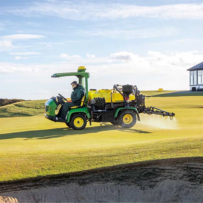 Ein Greenkeeper arbeitet auf einer Rasenfläche mit einer John Deere Feldspritze