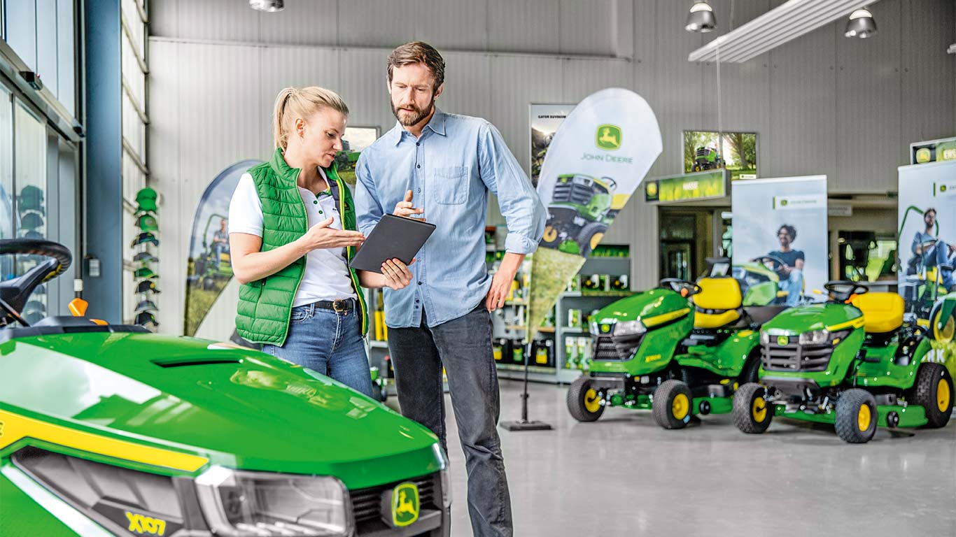 Ein John Deere Vertriebspartner berät einen Kunden beim Kauf eines John Deere Mähers.
