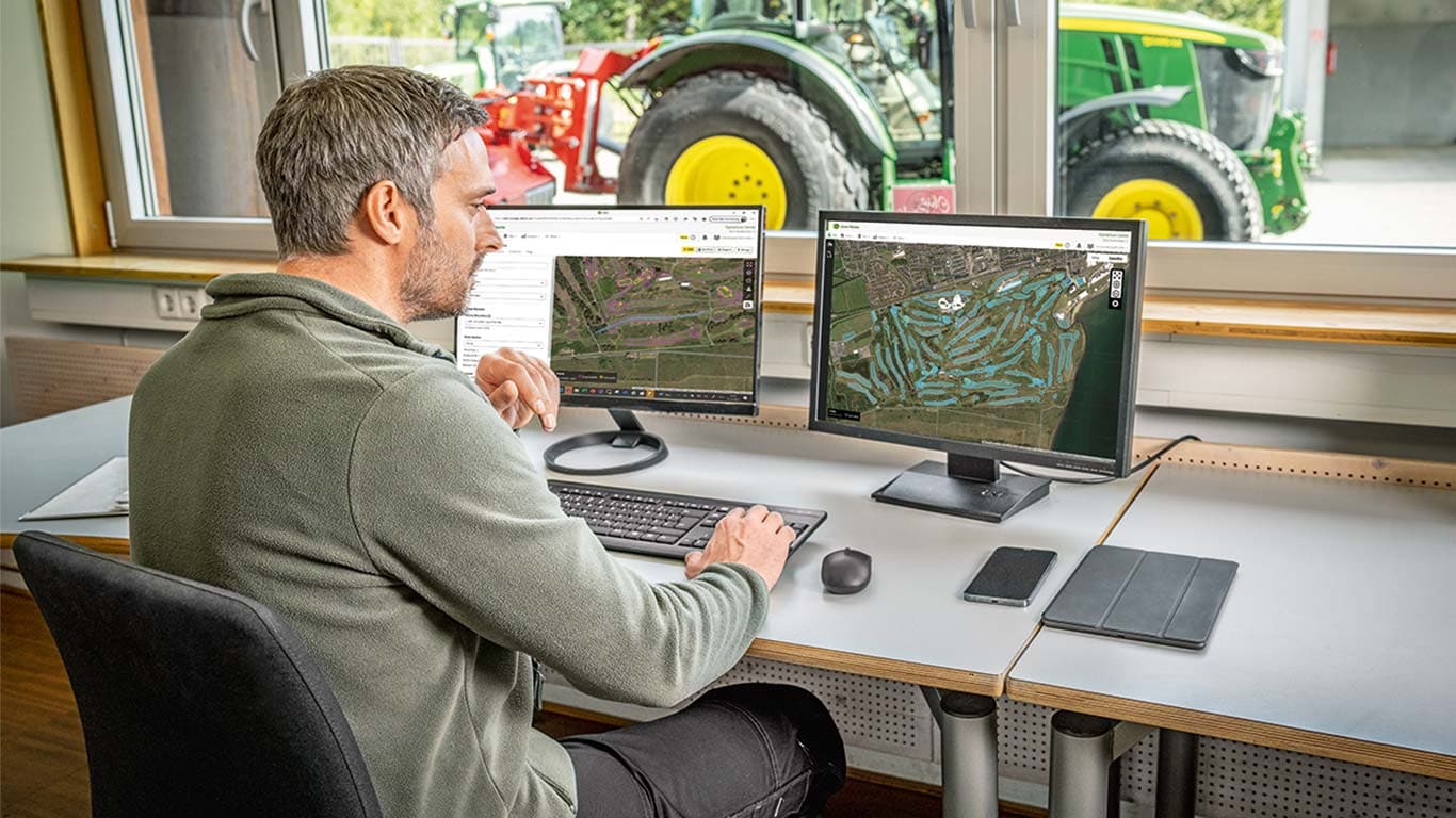 Ein Head Greenkeeper betrachtet die Karten eines Golfplatzes auf seinem Computer.