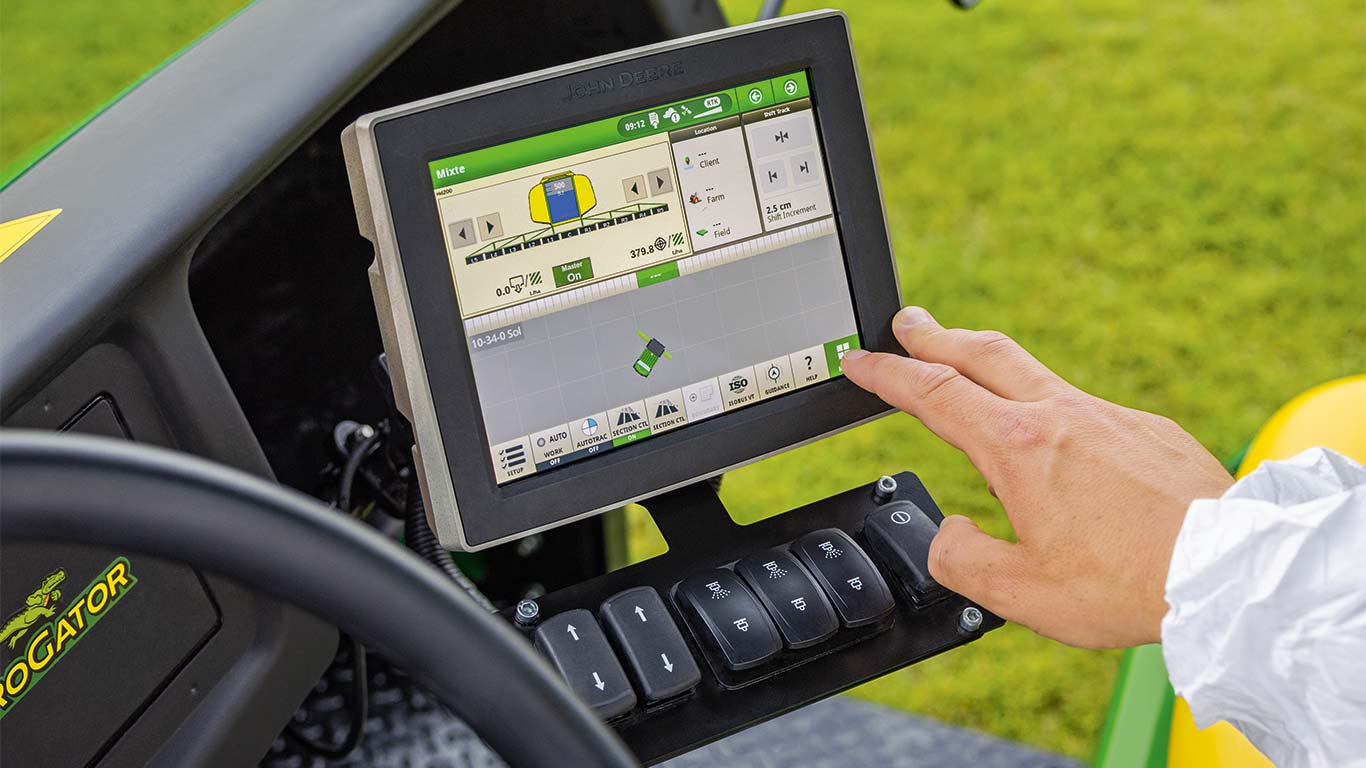 Ein Greenkeeper passt über das Display seines John Deere Mähers die Maschine an seine aktuelle Aufgabe an.