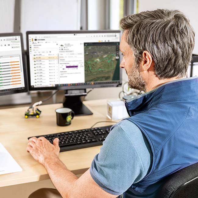 Ein Head Greenkeeper sitzt in seinem Büro und schaut sich die von der fortschrittlichen Rasenpflegetechnologie erfassten Daten an.