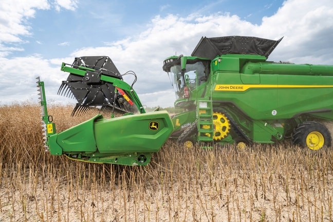 Gros plan sur la tête de récolte d’une moissonneuse-batteuse en plein travail, mettant en valeur les détails de la machine dans le champ