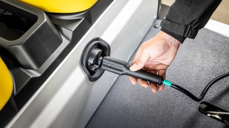 Branchement manuel d’un câble de recharge dans le port latéral d’un véhicule utilitaire Gator&nbsp;GS John&nbsp;Deere électrique.