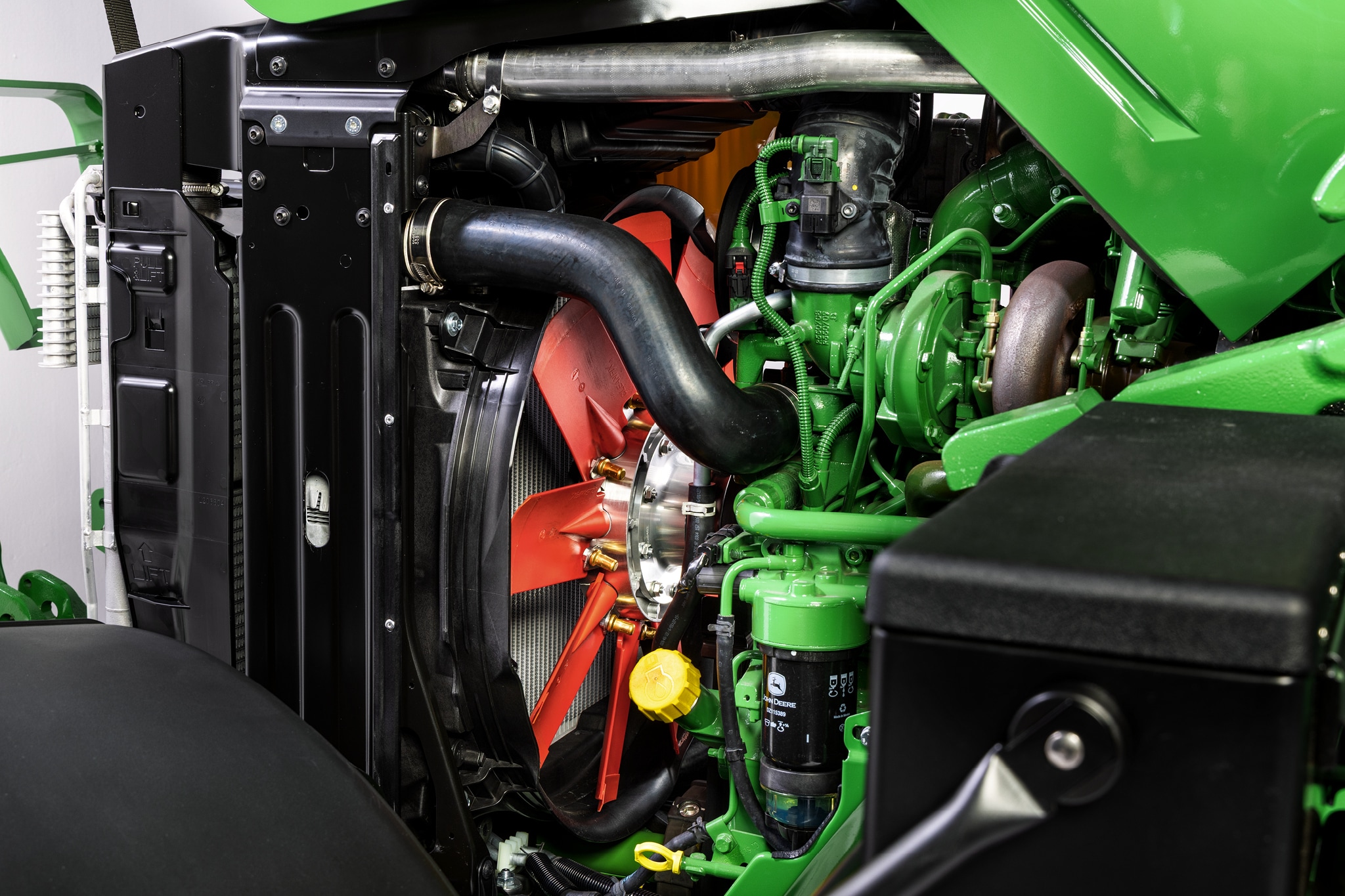 Nahaufnahme des Motorraums der Serie 6M von John Deere, in dem das Kühlsystem und die Motorkomponenten hervorgehoben werden.