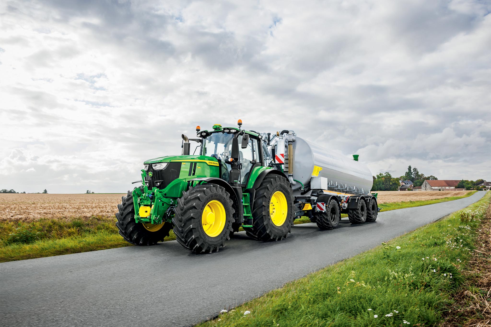 John Deere Traktoren der Serie 6M auf einem abgeernteten Feld mit breiten Grubber, von oben betrachtet mit aufsteigendem Staub.