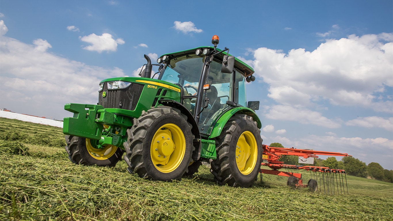 Ein John Deere Traktor beim Heuschwaden.